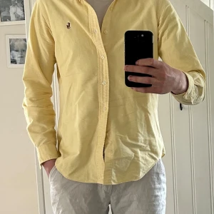 Gul skjorta från Ralph Lauren - Säljer en klassisk gul skjorta från Ralph Lauren med broderad logga på bröstet. Skjortan har lång ärm, knappar framtill och är tillverkad i bomull. Perfekt för sommaren. 