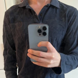 Långärmad piké Belstaff   - Säljer en mörkblå långärmad skjorta från Belstaff med diskret broderad logga på bröstet. Skjortan har klassisk krage och knappar framtill. Perfekt för dig som gillar stilrena plagg med en exklusiv touch. Storlek M men passar S