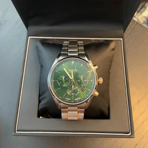 Grön klocka från BOSS - Snygg herrklocka från BOSS med grön urtavla, silverfärgad och gulddetaljerad länk i rostfritt stål. Klockan är knappt använd och i väldigt bra skick. Länkar tillkommer och låda tillkommer.