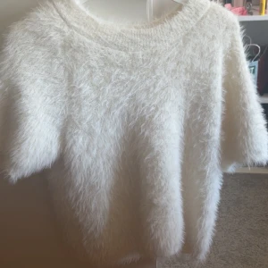 Vit fluffig stickad tröja - Supermjuk och fluffig vit stickad tröja med korta ärmar och rund hals. Tröjan har en loose passform och är perfekt för dig som gillar en mysig och trendig look. Nypris 499kr. Aldrig använt.