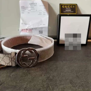 Beige skärp GG - Snyggt beige i silverfärgad metall. Bältet har klassisk form och detaljer med -mönster vid spännet. Perfekt accessoar för att lyfta din outfit med lyxig känsla.