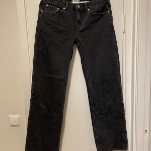 Svarta low rise jeans från 157, M - Svarta jeans från 157 i klassisk femficksmodell. Byxorna har låg midja (low rider) och raka ben med en avslappnad passform. Jeansen är tillverkade i denim och har silvriga nitar och knappdetaljer. Perfekta för en cool och enkel stil.