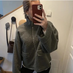  teddyjacka med dragkedja - Mysig teddyjacka med hög krage och två fickor framtill. Jackan har en rak, lite oversized passform och stängs med dragkedja. Perfekt för sommarkvällar🥰