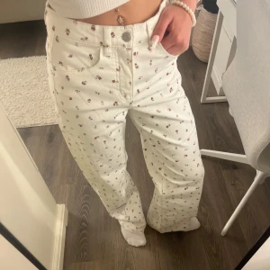 Blommiga vita wide jeans  - Säljer ett par vita högmidjade jeans med gulligt blommigt mönster köpta från Kappahl och aldrig använda!