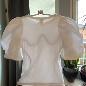 Vit puffärmad topp i bomull!  - Superfin vit topp med stora puffärmar och rund halsringning. Modellen är rak och har korta ärmar med extra volym, vilket ger en trendig och lekfull look. Perfekt att styla med jeans eller kjol för en cool vibe. Tillverkad i mjuk bomull som känns skön mot huden. Tröjan är i perfekt skick, som ny.                 SLUTSÅLD PÅ HM