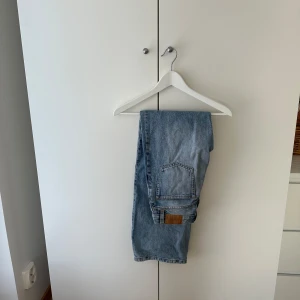 Ljusblå jeans från Monki, storlek 25 - Säljer ett par klassiska ljusblå jeans från Monki i storlek 25. Jeansen har raka ben, fem fickor och snygga kontrastsömmar. Tillverkade i bomull med en skön jeanskänsla. Perfekta för dig som gillar en enkel och tidlös look.