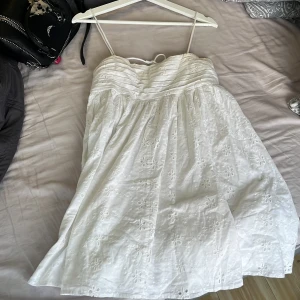 Vit  kortklänning med broderi - Superfin vit kortklänning med tunna axelband och broderade blommor, knyts i ryggen