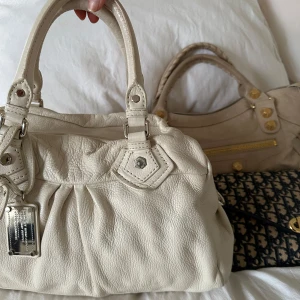 Vit Q Classic Boston Bag! - OBS! Åker utomlands imorgon, sista dag jag kan skicka är idag. Köp helst via min vinted @juliavallberg 🤎  Snyggaste vita handväskan i nyskick från Marc by Marc Jacobs i äkta läder med silverdetaljer och dubbla handtag. Välbevarad vintage modell! Perfekt för att ge en stilren touch till din outfit. Mått 40x22x15 cm (undersida). Kan hämtas hemma hos mig i Nacka eller skickas men kan tyvärr inte mötas🤍
