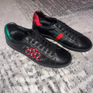 Gucci Ace sneakers med orm brodyr - ✨Svarta Gucci Ace sneakers i skinn✨ Perfekta för dig som vill sticka ut med lyxig streetstyle✨ De är i bra skick inga defekter lite använda skick 9/10. Säljs då de ej användes så mycket och är för små✨stl 40 men passar 41✨ pris är ej hugget i sten✨