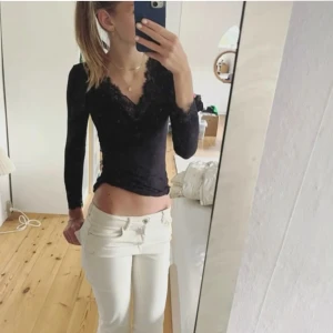 Svart långärmad topp med spets - Svart långärmad topp med v-ringning och fina spetsdetaljer vid halsringning och ärmslut. Sitter tight och har en feminin, stilren look som passar perfekt till jeans eller kjol. Enkel att styla för en trendig outfit. (Tröjan har ett litet hål kan sy ihop)
