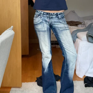 Lågmidjade jeans - Säljer dessa unika och coola lågmidjade bootcut jeansen med rosa detaljer på fickorna där bak. Har haft ett hål på ena insidan av benet men de är igensytt. Riktigt coola och trendiga jeans 