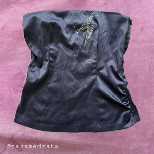 Gråblå tubtopp Fishbone med blixtdekor - Snygg tubtopp från Fishbone i satinliknande material. Toppen är axelbandslös och har en glittrig blixtdekor framtill med små stenar. Dragkedja i sidan för enkel påklädning. Perfekt för dig som vill sticka ut med en cool detalj.