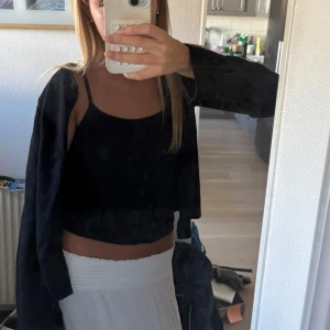 Svart cardigan jacka med knapp - Svart cardigan jacka med rund halsringning och en knapp framtill som skapar en liten öppning vid halsen. Jackan har lång ärm och är i ett mjukt, stickat material. Enkel och stilren modell som är lätt att matcha. Perfekt och snygg att ta bära vid kyligare sommarkvällar! ❣️