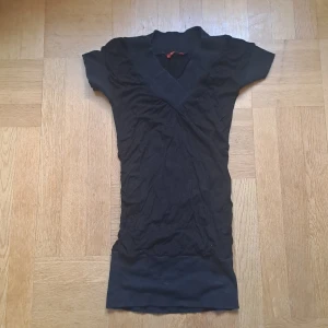 Svart lång topp med scrunch  - Svart lång topp från Sissie med v-ringad omlott och korta ärmar. Strechig och scrunch i sidan. Ribbad kant nertill och vid halsen. 🩷😊 Pris är diskuterbart vid snabb affär 