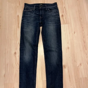 Mörkblå jeans från Jack & Jones - Säljer ett par mörkblå jeans från Jack & Jones, modell Tapered/Mike. Jeansen har klassisk femficksdesign, dragkedja och smalare ben med avsmalnande passform. Perfekta för dig som gillar en stilren och enkel look.