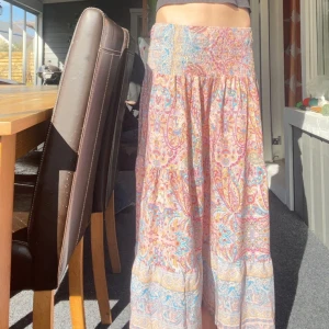 Färgglad långkjol - Säljer en superfin långkjol med färgglatt mönster i rosa, blått och orange. Strl vandrar från xxs-s men den passar för folk med M. Jag säljer den för att den är för kort för mig. Org pris är 599
