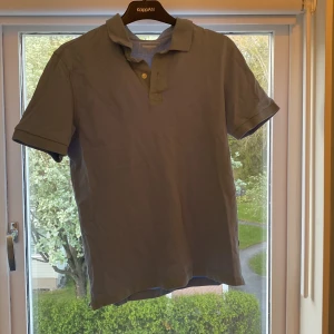 Ljusblå pikétröja från Dressmann - Säljer en ljusblå pikétröja från Dressmann i storlek M. Tröjan har korta ärmar, klassisk krage och knäppning med två knappar. Perfekt för en avslappnad och stilren look.