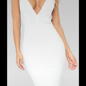 Vit v-ringad långklänning med paljetter  - Säljer en elegant vit långklänning med djup v-ringning och smala axelband. Klänningen är dekorerad med små paljetter över hela klänningen 