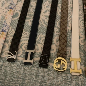 Fendi bälte med silverfärgat spänne - Säljer ett stilrent Fendi bälte i svart med klassiskt Fendi-mönster och ett stort silverfärgat F-spänne. Perfekt accessoar för att lyfta din outfit med en exklusiv touch.