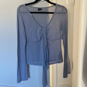 Ljuslila långärmad topp från Gina Tricot - Säljer en ljuslila långärmad topp från Gina Tricot. Toppen har v-ringning, knyt framtill och är tillverkad i ett tunt, lätt material. Perfekt för lager-på-lager eller som en snygg detalj till din outfit.