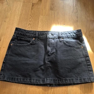 Svart jeanskjol från MNG - Säljer en svart jeanskjol från MNG i klassisk femficksmodell. Kjolen är kort och har både fram- och bakfickor samt bälteshällor. Perfekt att styla med en enkel topp eller hoodie. Lågmidjad o lite stor i storlek 