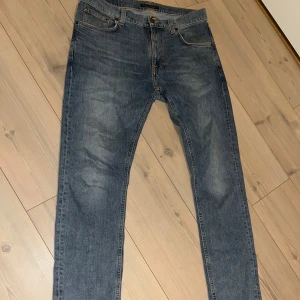 Blå jeans från Nudie Jeans - Säljer ett par klassiska blå jeans från Nudie Jeans, modell Lean Dean. Jeansen har normal passform, raka ben och fem fickor. Tillverkade i 98% bomull och 2% elastan för extra komfort. Perfekta för dig som gillar stilrena och tidlösa jeans.
