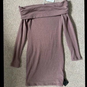 Långärmad klänning off-shoulder - Klänningen har långa ärmar och en bred, nedvikt krage som ger en avslappnad och trendig look. Perfekt för kyligare dagar och enkel att styla med boots eller sneakers.