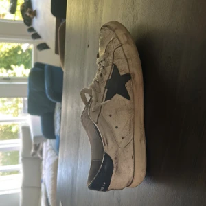 Vita sneakers från Golden Goose med blå stjärna - Säljer ett par vita sneakers från Golden Goose med blå stjärna på sidan. Har box och kvitto på skorna!