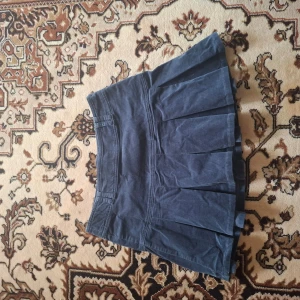 Mörkblå plisserad minikjol - Snygg mörkblå minikjol med plisserad design. Kjolen har en klassisk look och passar perfekt till många olika stilar. Tillverkad i ett mjukt material som känns bekvämt hela dagen.