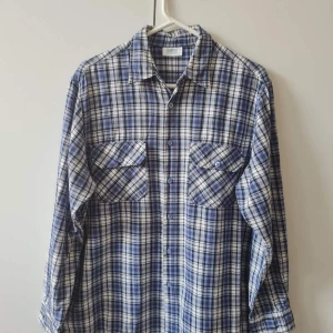 Blårutig skjorta från WORKER strl L - Snygg blårutig skjorta från WORKER med klassisk krage och två bröstfickor med knappar. Skjortan har långa ärmar och är tillverkad i 100% bomull. Bröstmått 114cm. Storlek L. Kan hämtas i Vallentuna.