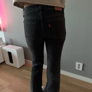 Svarta Levis 501 jeans - Säljer ett par svarta Levis 501 jeans med klassisk rak passform och fem fickor. Jeansen har normalhög midja och raka ben, perfekt för en stilren look. Ikonisk Levis-lapp bak och röd etikett på bakfickan.