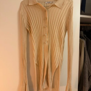 Kofta - Säljer en beige ribbad kofta från NA-KD i storlek S. Tröjan har långa ärmar och knappar framtill 💛