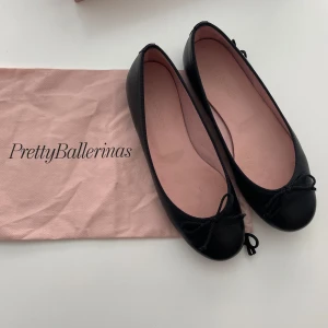 Svarta ballerinaskor från Pretty Ballerinas - Svarta ballerinaskor från Pretty Ballerinas med rund tå och rosett framtill. Skorna är tillverkade i äkta läder. Nypris är ca 1700. Använda 1-2 gånger, så i mycket bra skick. Står storlek 37 men är små i storlek så skulle säga 36. 