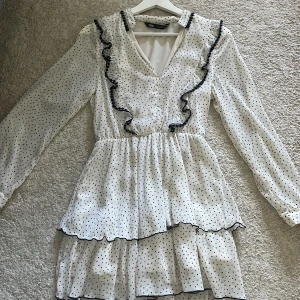 Vit prickig Zara klänning - Säljer min vita prickiga Zara klänning med volanger!! Klänningen har v-ringning, långa ärmar och storlek XS. Endast använd fåtal gånger. Perfekt för vår och sommar!🌸🥰