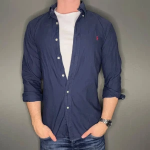 Mörkblå Ralph Lauren skjorta - Hej säljer nu min fina Ralph lauren skjorta i storlek M. Den är i nyskick och kommer vara otroligt snygg nu i vår och framåt sommaren. Den har ett litet märke vid ena sidan av armen men inget stort! Nypris cirka 1600kr! Vi kommer att sälja liknande produkter nu i vår och närmare sommar så glöm inte följa profilen!🌊🍾