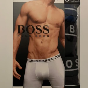 Vita boxerkalsonger från Hugo Boss - Snygga vita boxerkalsonger från Hugo Boss med bred resår i midjan där loggan står tryckt runtom. Klassisk och stilren design som passar perfekt till vardags. Materialet är mjukt och stretchigt för bästa komfort.