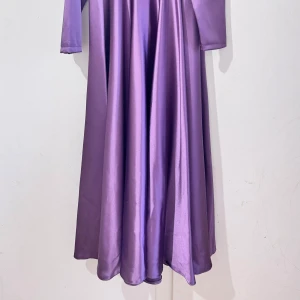 Lila lång festklänning - Säljer en glansig lila långklänning från Tane i storlek 38. Klänningen har lång ärm och ett svepande fall i ett satinliknande material som ger en lyxig känsla. Perfekt för dig som vill sticka ut med en elegant look.