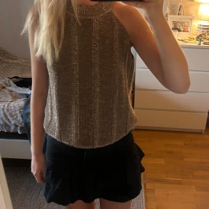 Glittrig stickad halternecktopp  - Supersnygg glittrig stickad topp i guld med ribbade detaljer och hög hals. Använd nån gång men i väldigt bra skick! 