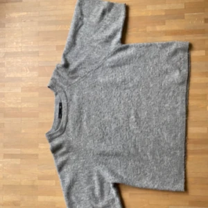 Grå stickad tröja från 157 - Mysig grå stickad tröja från 157  med klassisk rund halsringning och kortare ärmar. Populär och passar till mycket.