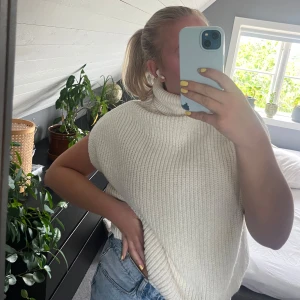 Vit stickad tröja - NA-KD - Säljer en krämvit, ribbstickad tröja från NA-KD med hög polokrage och breda ärmhål. Västen har en loose fit och är perfekt att slänga över en skjorta eller t-shirt. Storlek S