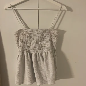 Vit smockad linnetopp Gina Tricot - Supersöt vit tooo från Gina Tricot, det går att ta bort axel banden så det blir en tub topp. 