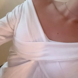 Vit topp med lång ärm - Supersnygg vit topp med långa ärmar och  omlottdetalj över bysten. Vet inte vart den är ifrån men står stl M, skulle säga sitter som S