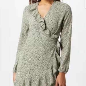 Prickig omlottklänning från ONLY - Superfin kort omlottklänning från ONLY i grön med svarta prickar. Klänningen har långa ärmar, volangdetaljer vid halsringningen och nederkanten samt knyt i midjan. Perfekt för dig som gillar en söt och trendig look. Aldrig använd. Eftersom det är en omlott känning och man knyter den själv passar den xs-m