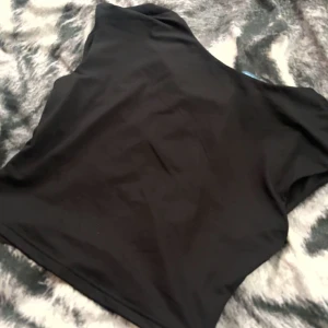 Svart asymmetrisk topp från SHEIN - Svart, stilren topp från SHEIN i storlek M. Öppen rygg och helt oanvänd