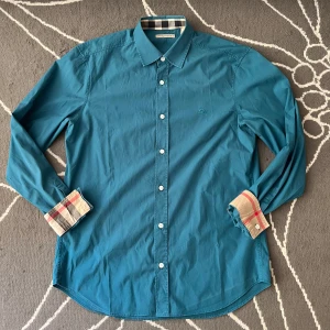 Burberry skjorta turkos - Burberry skjorta turkos i bra skick, inga tecken på slitage, använd en del. Endast skjortan ingår.