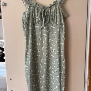 Grön blommig klänning från SHEIN - ❗️SKRIV TILL MIG VID KÖP❗️Supersöt ljusgrön klänning från SHEIN med vita små blommor, volangdetaljer på axelbanden och knytning framtill. Ribbad struktur i tyget. Använt nån gång. 