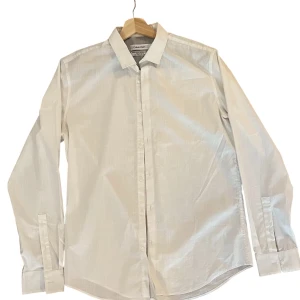 Vit skjorta från Calvin Klein M - Klassisk vit skjorta från Calvin Klein i body fit-modell. Skjortan har lång ärm, knappar framtill och stilren krage. Den är i väldigt bra skick! 