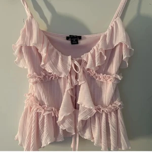 Ljusrosa volangig linnetopp med knyt - fin ljusrosa tröja med volanger , storlek M men skulle säga att den sitter som en S 💕