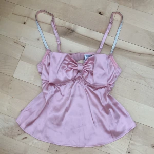 Rosa satin linnetopp med rosett - Supergulligt rosa linne från New Yorker, aldrig använt och i mycket bra skick :) Säljer för 60kr, pris kan diskuteras 🪽