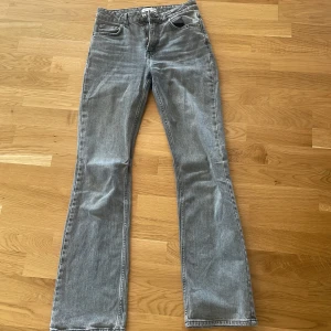 Grå bootcut jeans - Snygga grå jeans med bootcut-modell och klassisk femficksdesign. Jeansen har en något utsvängd passform nertill och är tillverkade i ett mjukt denimtyg. Perfekta för en avslappnad och trendig look.